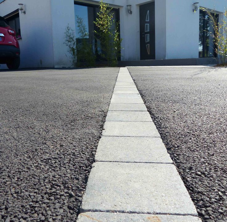 Smooth modern tar driveway with a brick paving inlay strip leading to a contemporary home