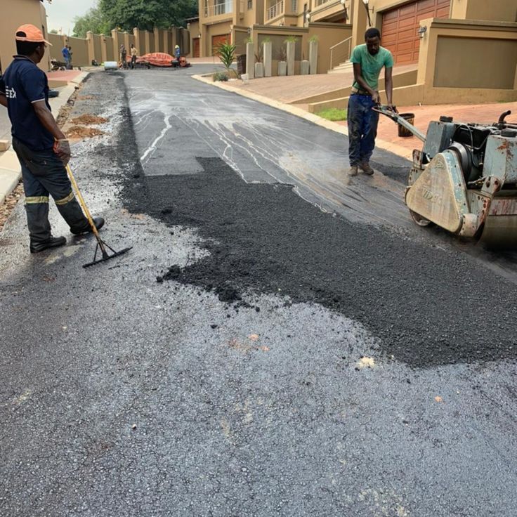 Ramp Tar Projects team laying tar in a residential complex driveway, using a vibrating plate compactor
